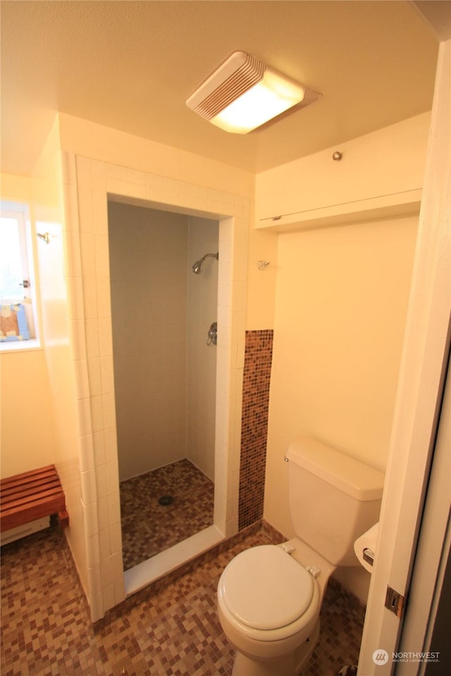 bathroom featuring tiled shower and toilet