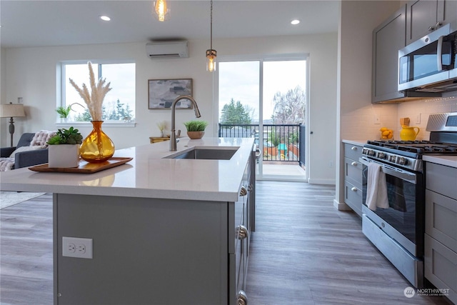 kitchen featuring gray cabinets, hanging light fixtures, stainless steel appliances, and sink