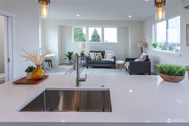 kitchen with sink, hanging light fixtures, and a wall unit AC