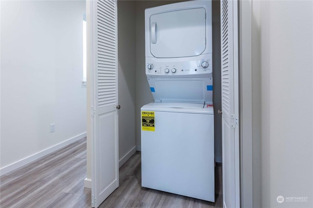 laundry area featuring wood-type flooring and stacked washer / drying machine