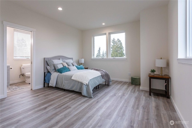 bedroom featuring connected bathroom and light hardwood / wood-style flooring