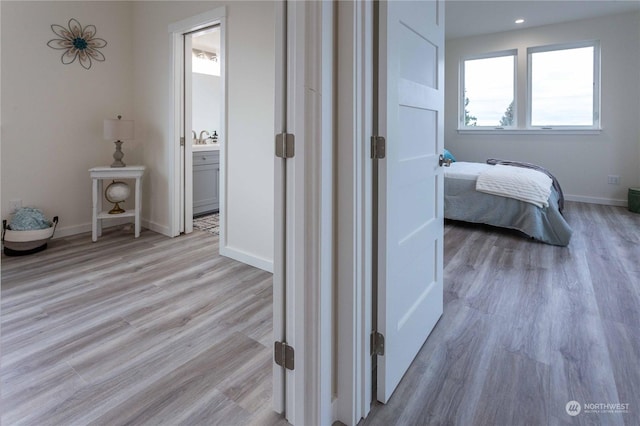 corridor with light wood-type flooring and sink