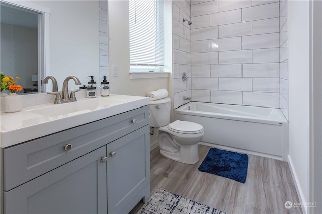 full bathroom with hardwood / wood-style floors, vanity, toilet, and tiled shower / bath