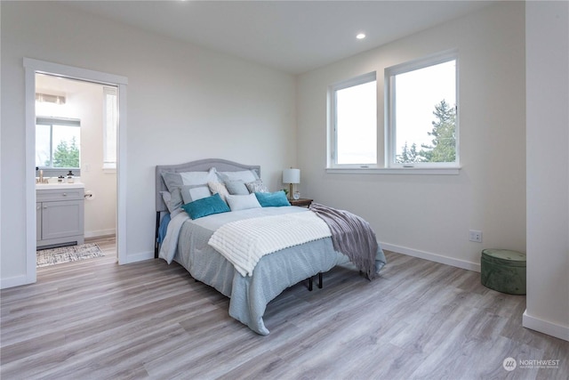 bedroom with light wood-type flooring and ensuite bath