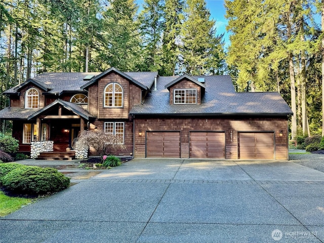 view of front of home with concrete driveway, a garage, and a shingled roof