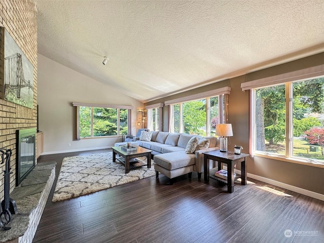 living area featuring dark wood finished floors, plenty of natural light, a brick fireplace, and lofted ceiling