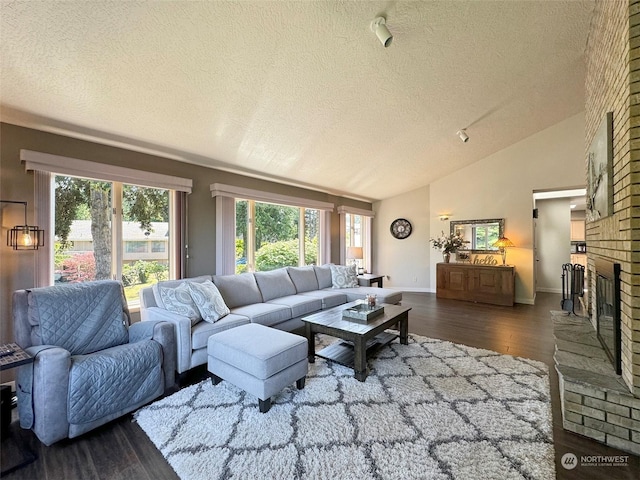 living room with baseboards, vaulted ceiling, a fireplace, wood finished floors, and a textured ceiling