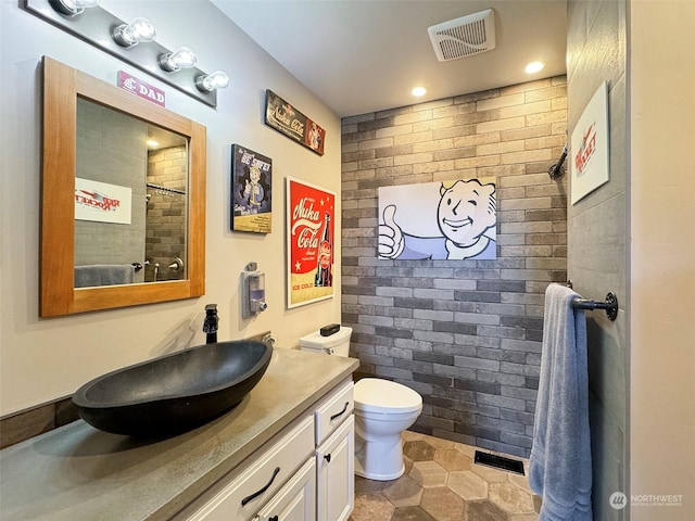 bathroom featuring vanity, toilet, visible vents, and a tile shower