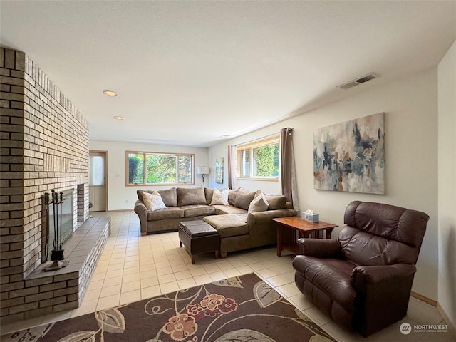 living room featuring light tile patterned floors, visible vents, a fireplace, and baseboards