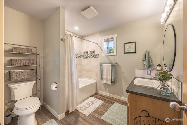 bathroom featuring baseboards, toilet, shower / bath combo, wood finished floors, and vanity