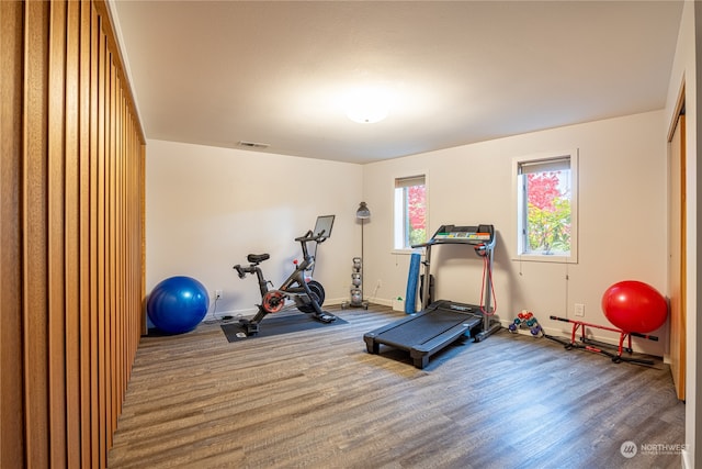 exercise room featuring visible vents, baseboards, baseboard heating, and wood finished floors