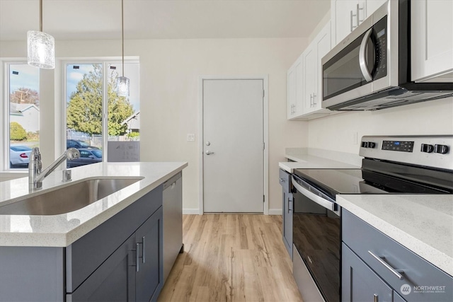 kitchen featuring white cabinetry, appliances with stainless steel finishes, sink, and hanging light fixtures