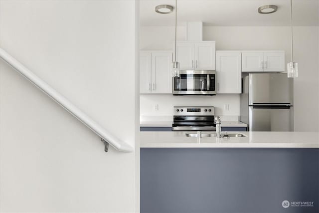 kitchen featuring white cabinetry, stainless steel appliances, decorative light fixtures, and sink