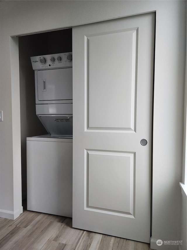 laundry room featuring stacked washer and clothes dryer and light hardwood / wood-style floors