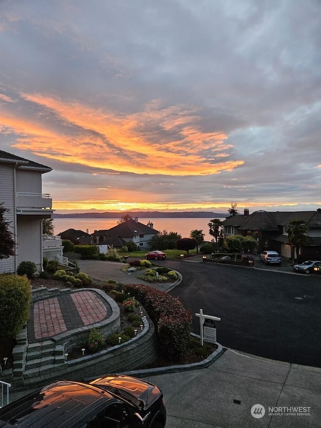 parking at dusk featuring a water view