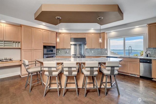 kitchen featuring a center island, sink, light brown cabinets, a water view, and appliances with stainless steel finishes