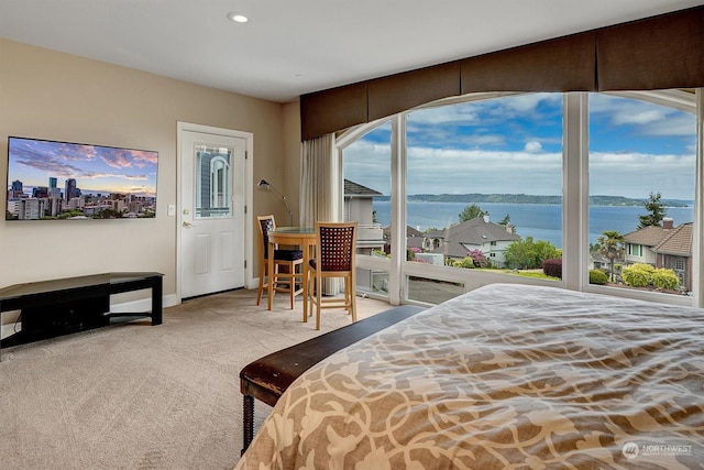 bedroom featuring light carpet, a water view, and multiple windows