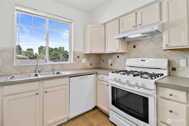 kitchen with sink, white appliances, plenty of natural light, and light tile patterned flooring