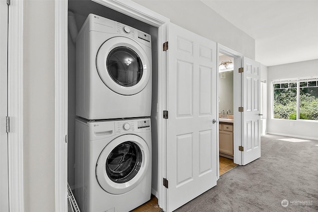 laundry room with sink, stacked washer / drying machine, and light colored carpet