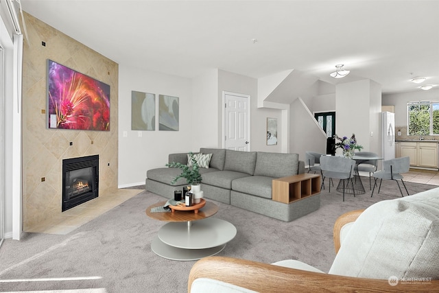 living room with a tile fireplace, sink, and light carpet