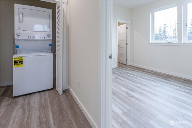 washroom with light hardwood / wood-style floors and stacked washer and clothes dryer