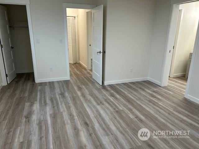 unfurnished bedroom with a spacious closet, light hardwood / wood-style flooring, and a closet