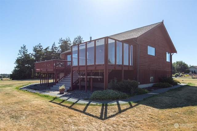 rear view of property featuring a wooden deck, a yard, and a sunroom