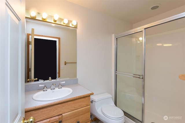 bathroom with vanity, toilet, and a shower with shower door