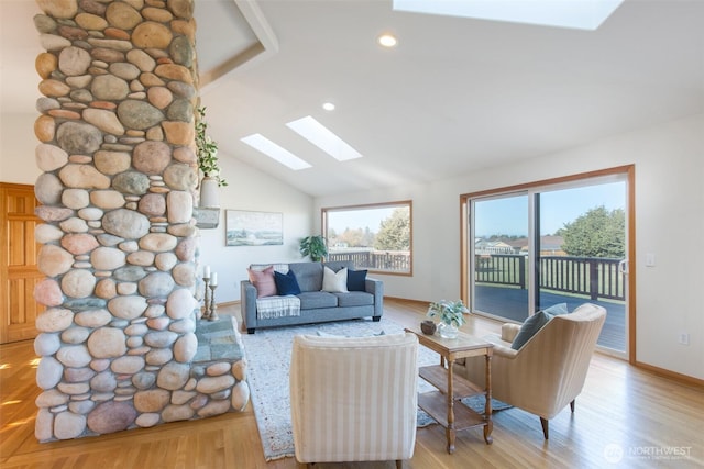 living room with vaulted ceiling with skylight and light hardwood / wood-style floors