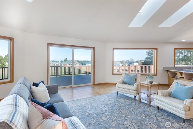 living room with hardwood / wood-style flooring and vaulted ceiling with skylight