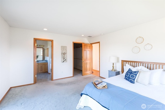 bedroom featuring a walk in closet, connected bathroom, a closet, and light carpet