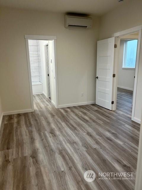 empty room with a wall unit AC and hardwood / wood-style floors