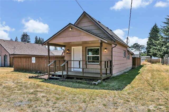 bungalow-style house with a wooden deck and a front lawn