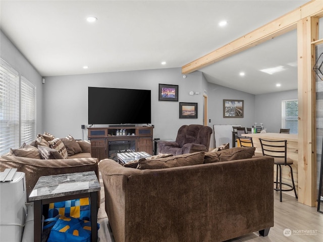 living room featuring lofted ceiling with beams, light hardwood / wood-style floors, and plenty of natural light