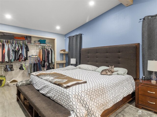 bedroom featuring light hardwood / wood-style flooring, a closet, and lofted ceiling