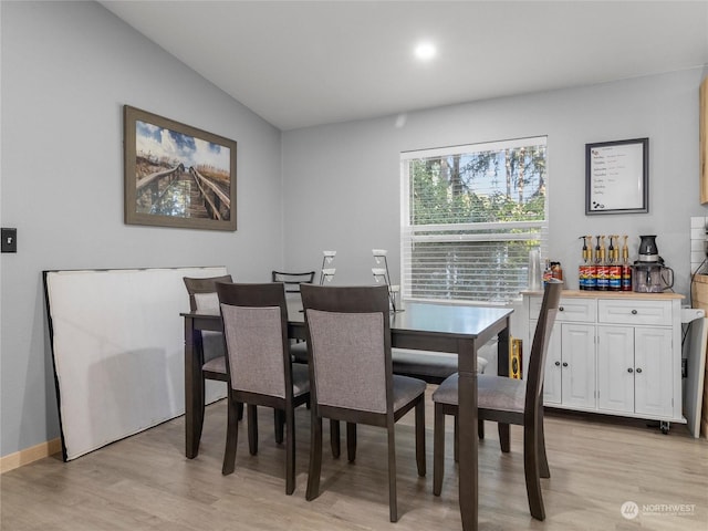 dining room featuring light wood-type flooring and vaulted ceiling