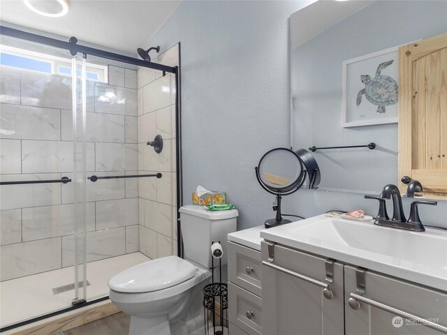 bathroom featuring walk in shower, vanity, wood-type flooring, and toilet