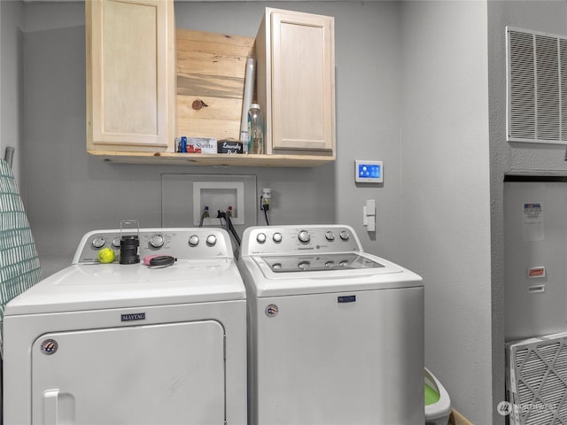 clothes washing area with cabinets and washer and dryer