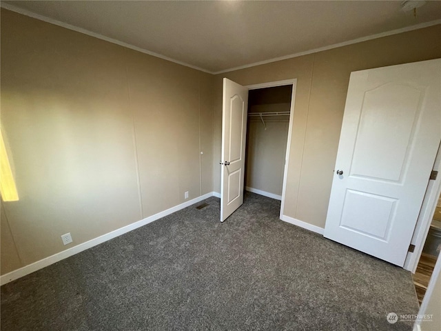 unfurnished bedroom with dark carpet, ornamental molding, and a closet