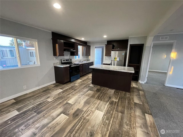 kitchen with stainless steel appliances, a kitchen island, hardwood / wood-style flooring, and dark brown cabinets