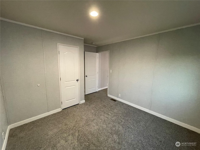 unfurnished bedroom featuring crown molding and dark carpet