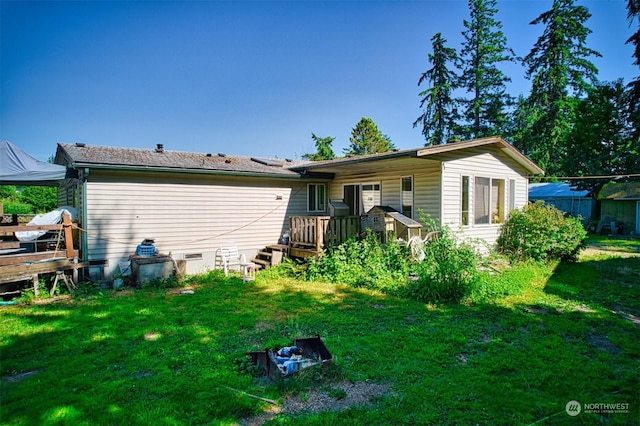 rear view of house featuring a lawn and a deck