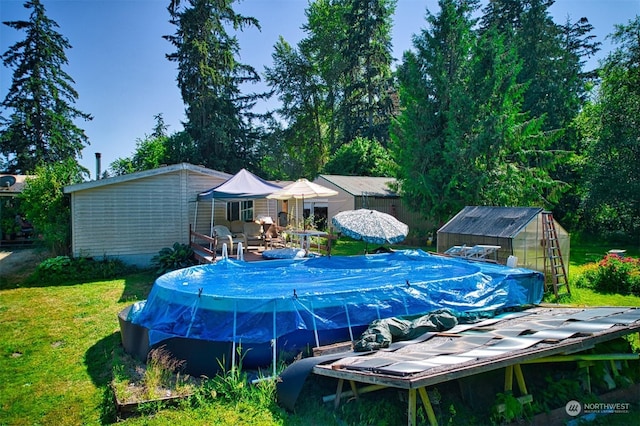 view of pool featuring a yard and an outbuilding