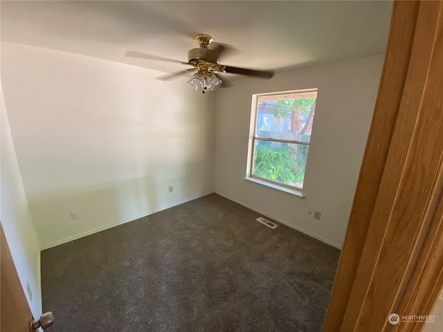 spare room with dark colored carpet and ceiling fan