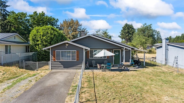 view of front of property featuring aphalt driveway, a patio area, fence, and a front yard