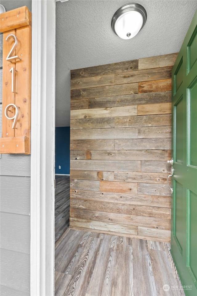 room details with a textured ceiling, wood walls, and wood finished floors