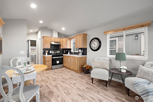 kitchen with decorative backsplash, stainless steel appliances, lofted ceiling, and light hardwood / wood-style floors