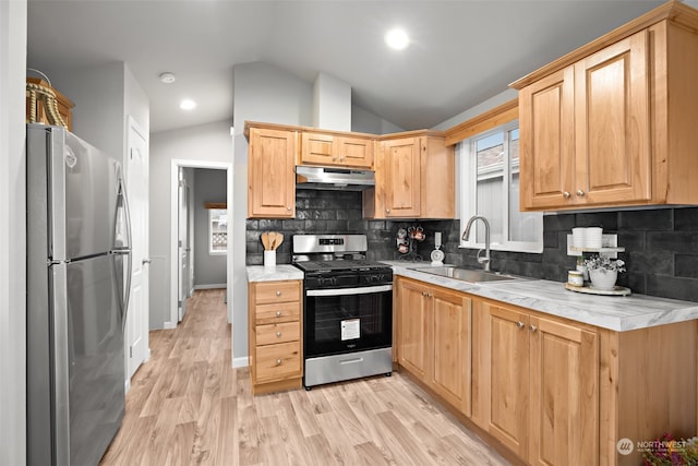 kitchen with lofted ceiling, backsplash, sink, light wood-type flooring, and appliances with stainless steel finishes