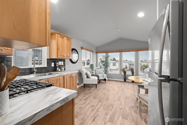 kitchen with sink, vaulted ceiling, light wood-type flooring, tasteful backsplash, and stainless steel appliances