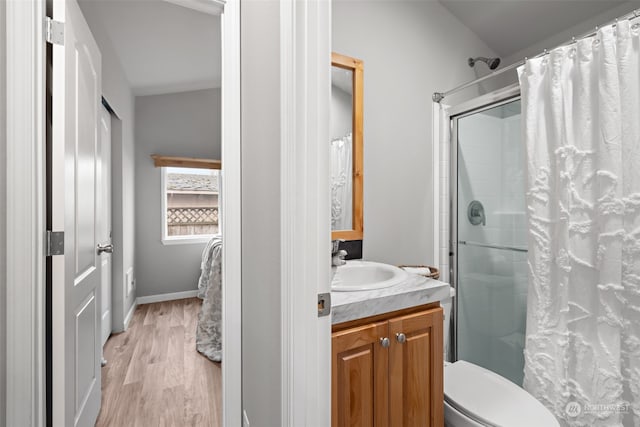 bathroom with hardwood / wood-style flooring, vanity, curtained shower, and toilet